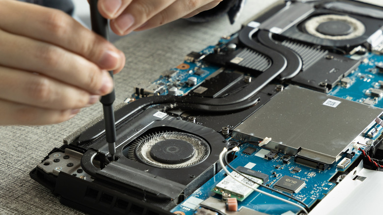 An open laptop with two cooling fans, heat pipes and the motherboard exposed.